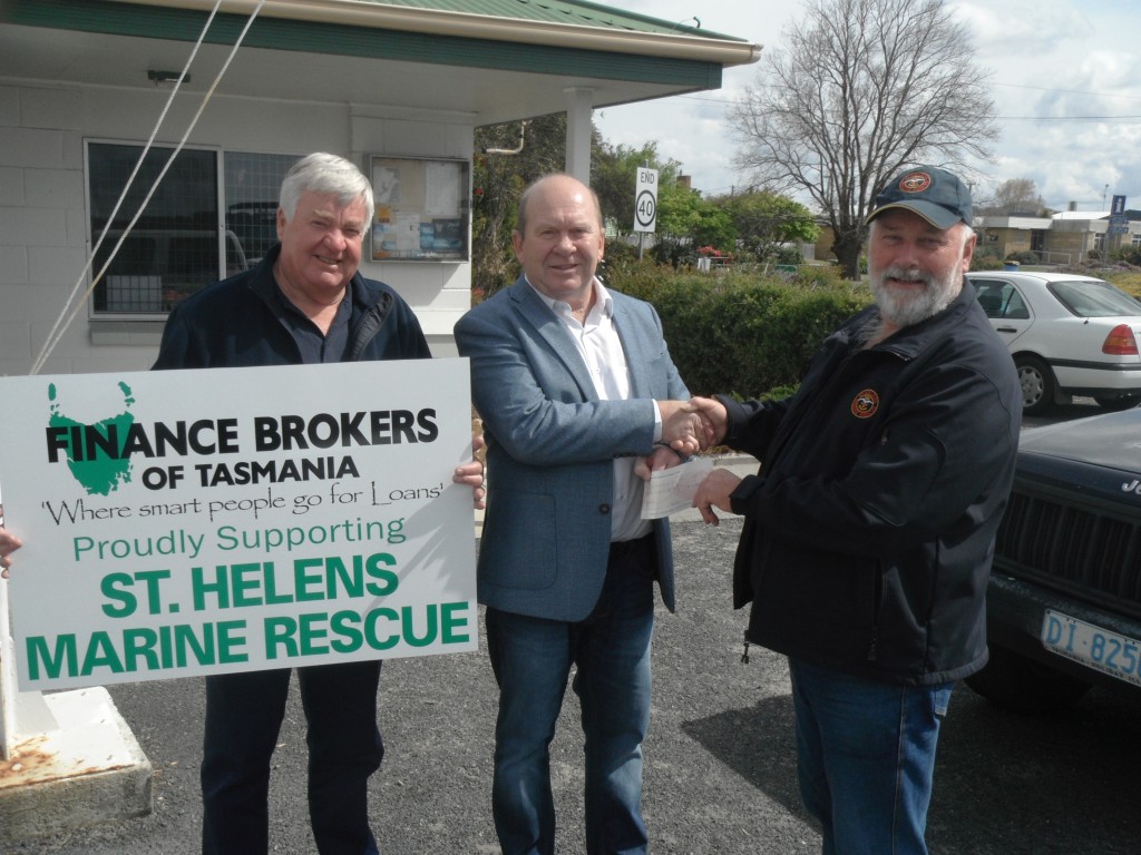 Paul Young holds the Finance Brokers of Tasmania's sponsorship announcement while director of FBT Lance Cure presents President John Dearing with sponsorship.